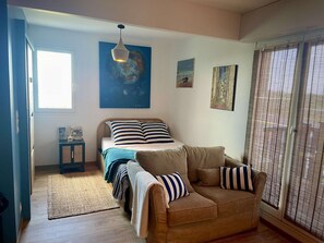 A bedroom with a bed, a sofa, a small cabinet, and artwork on the walls.