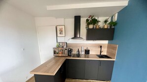 A compact kitchen with a wooden countertop, a built-in microwave, a coffee maker, and a sink. - Joli Studio Avec Balcon en Bord de mer (Cabourg)