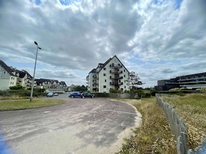A residential area with a multi-story apartment building, a curved road, and parked cars.
