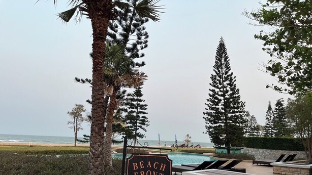 Schild für einen Strandpoolbereich mit Liegestühlen und Blick auf das Meer.