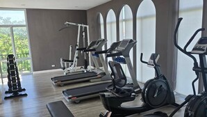 Ein modernes Fitnessstudio mit Laufbändern, Crosstrainern und Langhantelbänken.