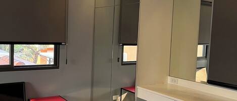 A modern room with a large mirror, a red bench, and a ceiling fan.