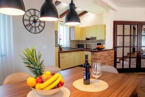 Enjoy a meal for two in this inviting dining area, complete with a table set and a modern kitchen in the background.