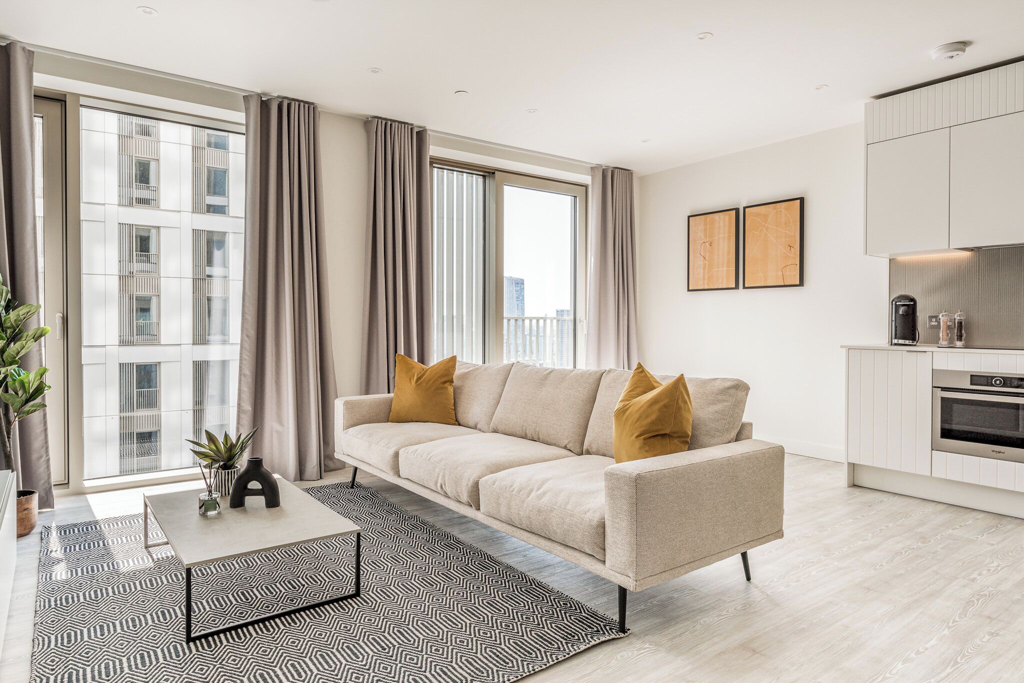 A modern living room with a sofa, a coffee table, and a kitchen area with cabinets and appliances.