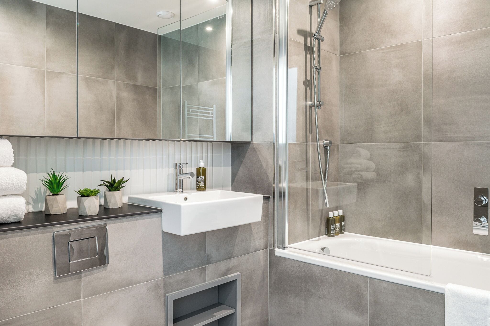 Une salle de bain moderne avec une douche à parois de verre, un lavabo blanc et une baignoire.