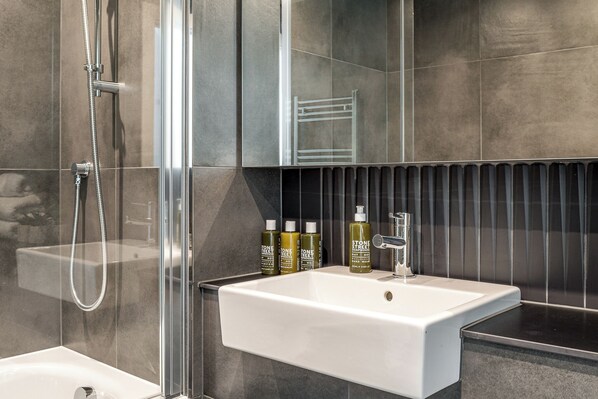 A modern bathroom with a glass-enclosed shower, a white sink, and a mirror above it.