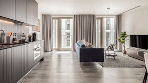 A modern kitchen with a built-in oven and a dining area with a sofa and a coffee table. - Urban Rest Stratford (London)