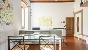 Un comedor con una mesa de vidrio, sillas de mimbre y un banco.