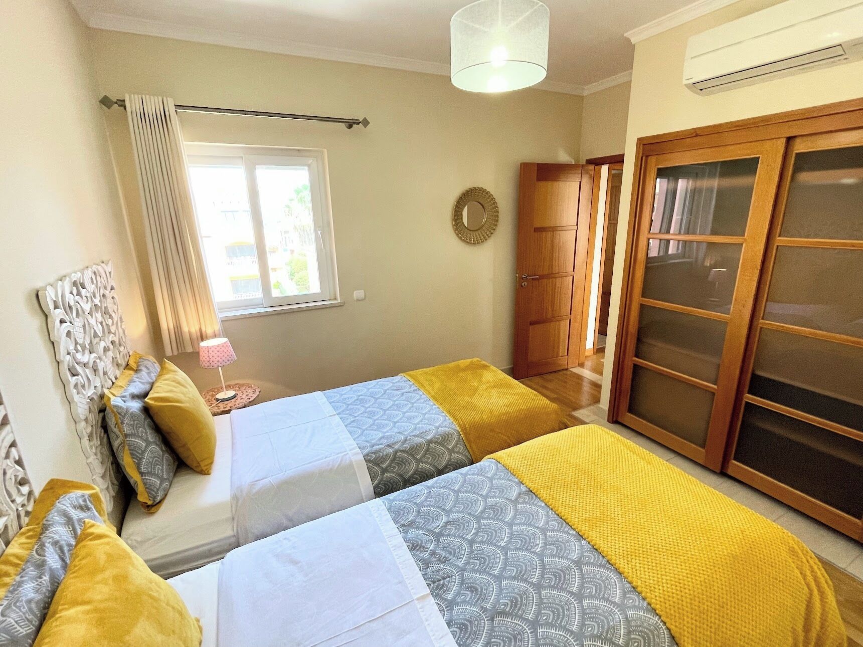 Un dormitorio con dos camas, una ventana con cortinas, un armario de madera y un ventilador de techo.