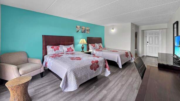 Una habitación de hotel con dos camas, un sofá, una mesita auxiliar y una televisión.