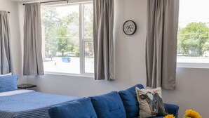 Un salon moderne avec un canapé bleu, une table basse en bois et un lit recouvert d’une couvre-lit à rayures.