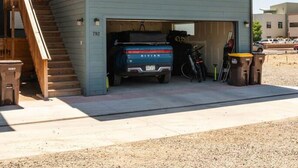 Une maison à deux étages avec un garage qui abrite un camping-car bleu et un vélo.