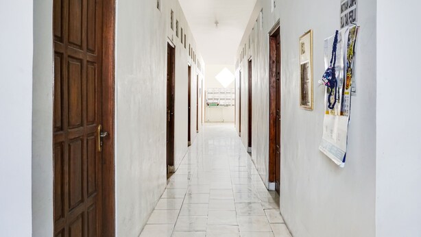 Passadís amb portes de fusta i terra de rajola, que condueix a una habitació amb finestra.