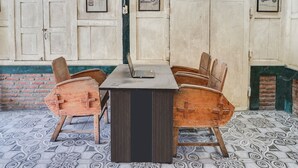 Una habitació amb taula i cadires de fusta, un ordinador portàtil sobre la taula, i un paviment amb dibuixos.