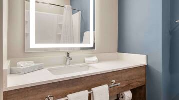 A bathroom with a white sink, a mirror, a towel rack, and a wooden vanity.