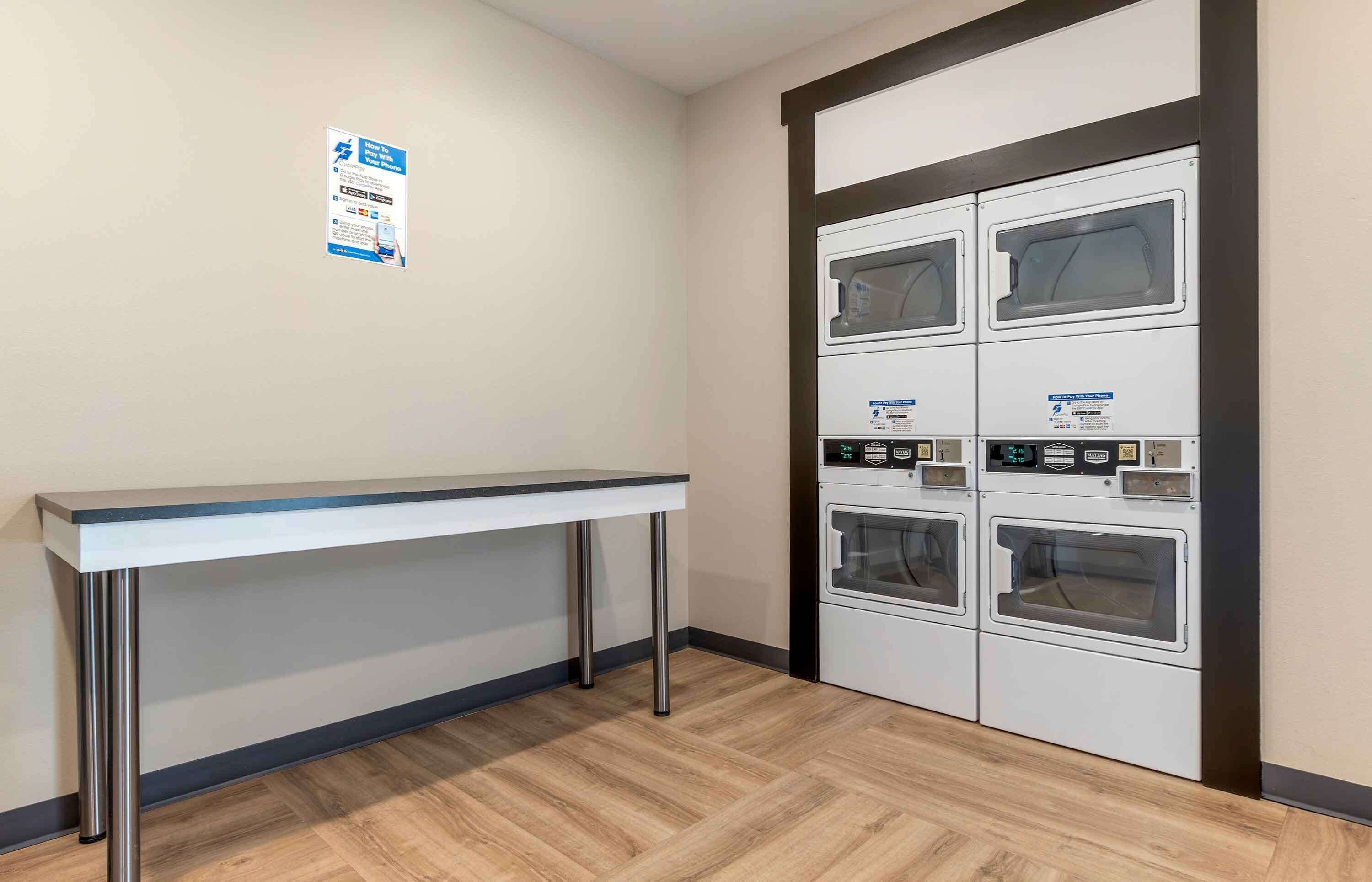 A laundry room with a table and four washing machines.
