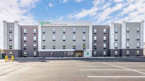 Un hotel moderno con fachada plana, múltiples ventanas y una entrada central con un logotipo verde.