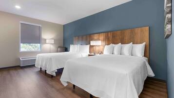 Habitación de hotel con dos camas, un ventanal con persianas, una lámpara de pie y una obra de arte en la pared.