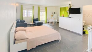 A modern hotel room with a bed, a small seating area with a table and chairs, a kitchenette, and a bathroom. - La Santa Clara - Studio climatisé (Saint-Pierre)