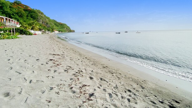 A beach with footprints, a clear sky, and boats in the water. - La Santa Clara - Studio climatisé (Saint-Pierre)