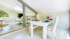 Un comedor moderno con una mesa y banco blancos, un tragaluz y vistas a un paisaje verde.