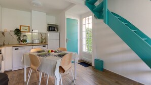 Uma cozinha compacta com armários brancos, micro-ondas e uma área de refeições com mesa posta para dois.