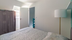 Quarto com cama, porta para outro cômodo, luminária e janela.