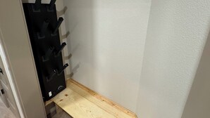 A corner of a room with a wooden bench and a black rack with hooks.