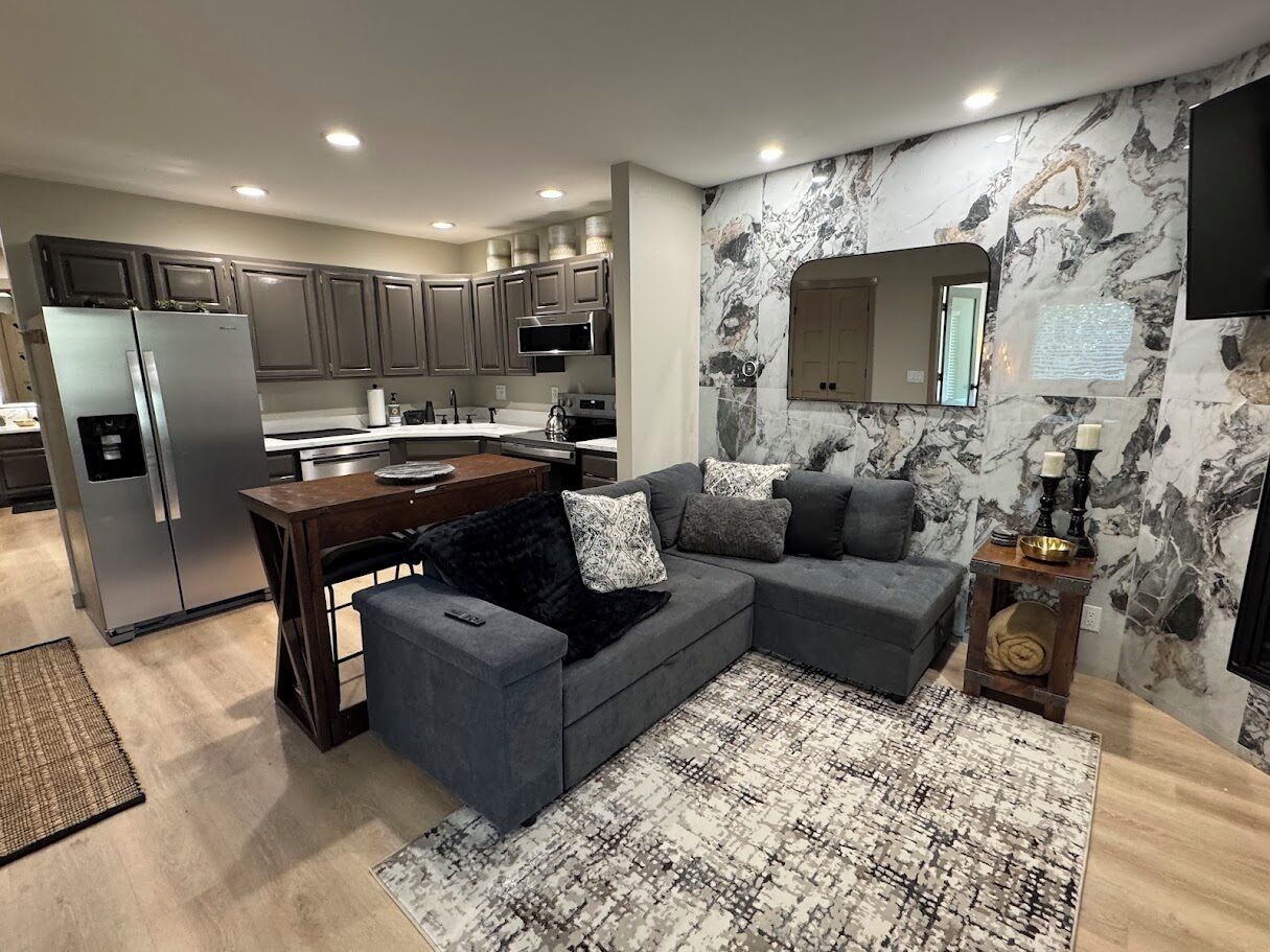 A modern kitchen with grey cabinets, a built-in microwave, and a refrigerator.