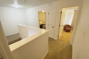 A staircase leading to a landing with a white wall and a door.