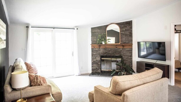 A living room with a stone fireplace, a television, and a sofa.