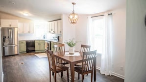 A modern kitchen with white cabinets, stainless steel appliances, and a dining area with a wooden table and chairs.