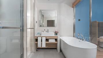 A modern bathroom with a freestanding bathtub, a glass shower enclosure, and a vanity with a mirror and towel rack.