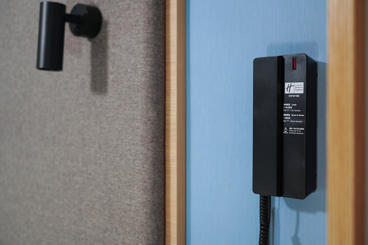 A black telephone mounted on a wall with a label indicating it is a hotel phone.