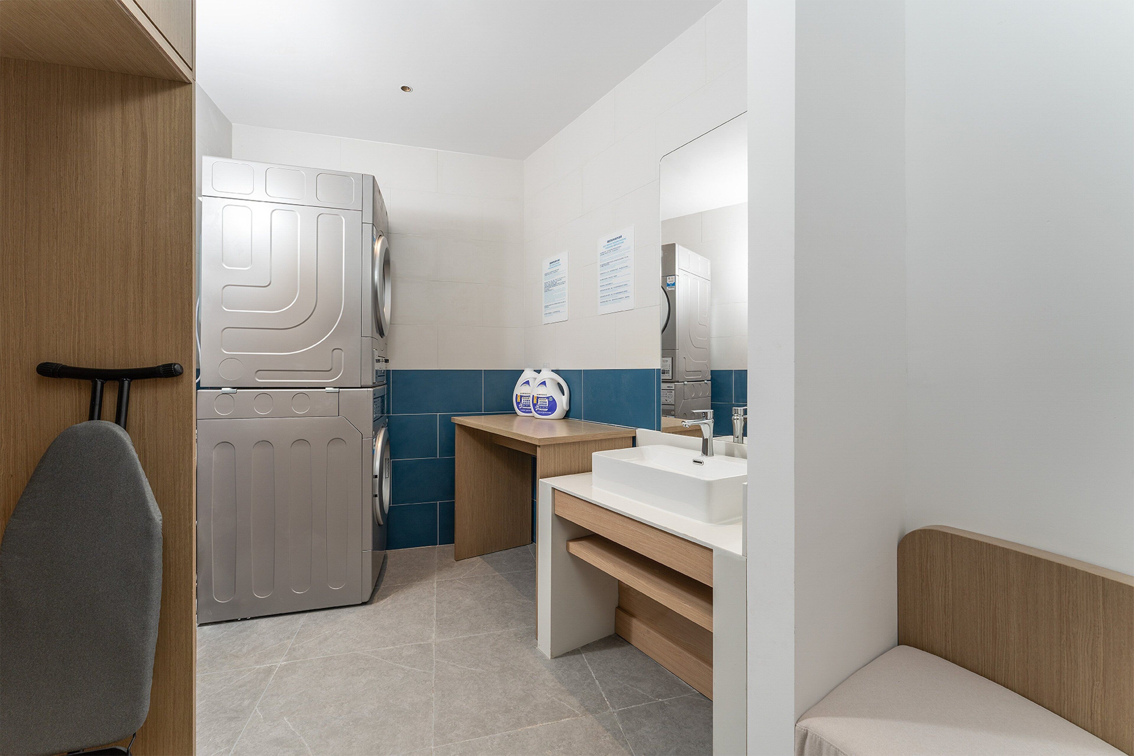 A compact bathroom with a built-in washing machine, a sink, and a mirror.