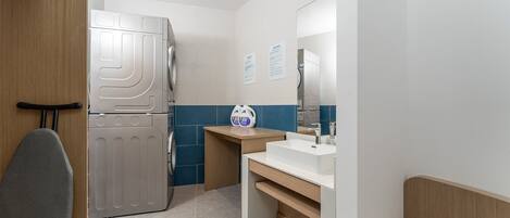 A compact bathroom with a built-in washing machine, a sink, and a mirror.