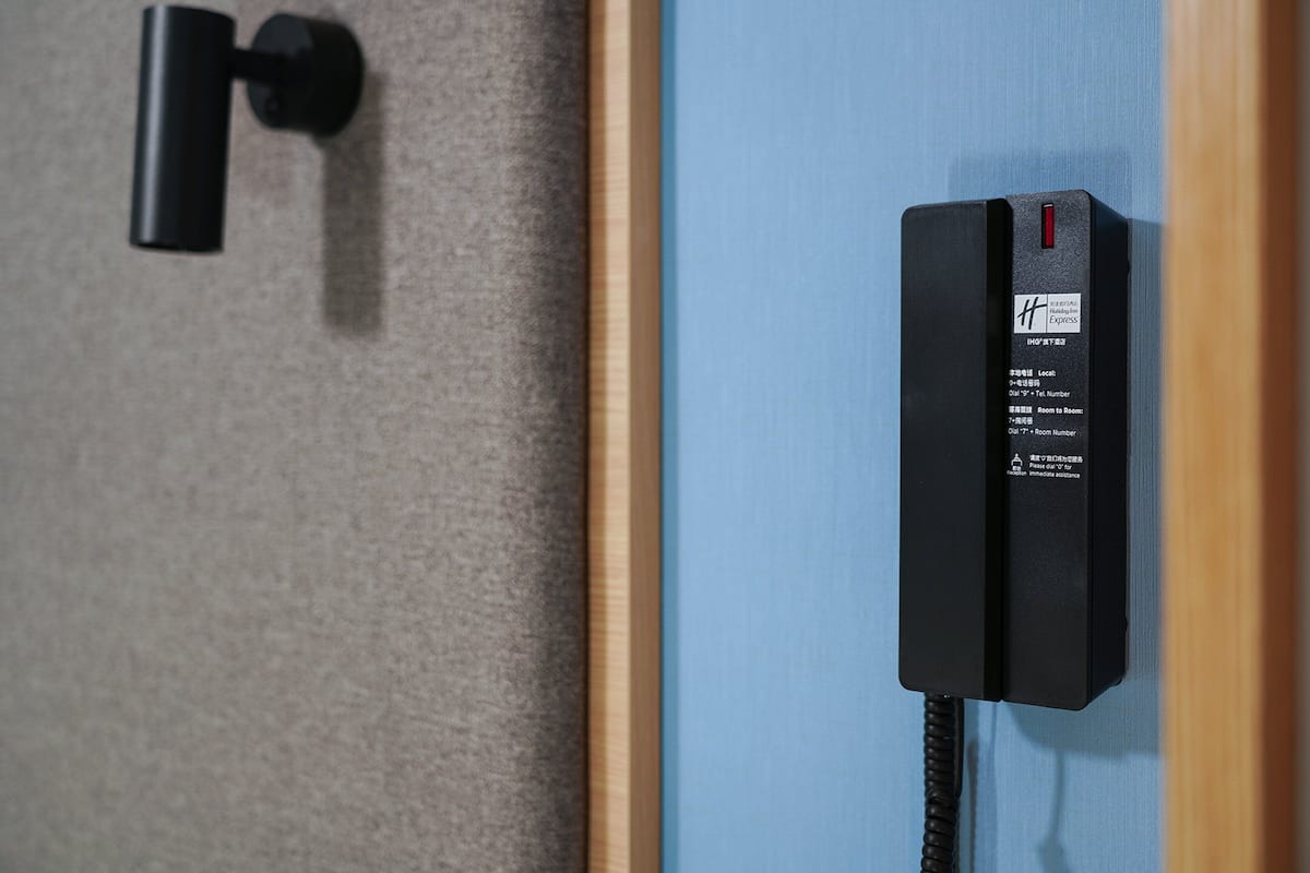 A black telephone mounted on a wall with a label indicating it is a hotel phone.