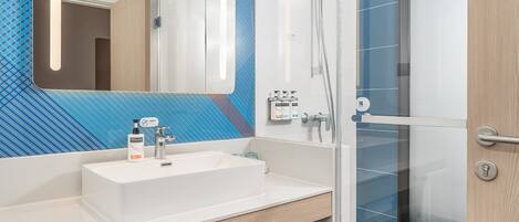 A modern bathroom with a white sink, mirror, and shower.