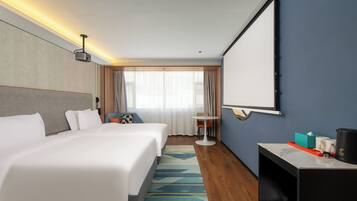 A hotel room with a large bed, a desk with a coffee maker, a small table, and a large mirror.