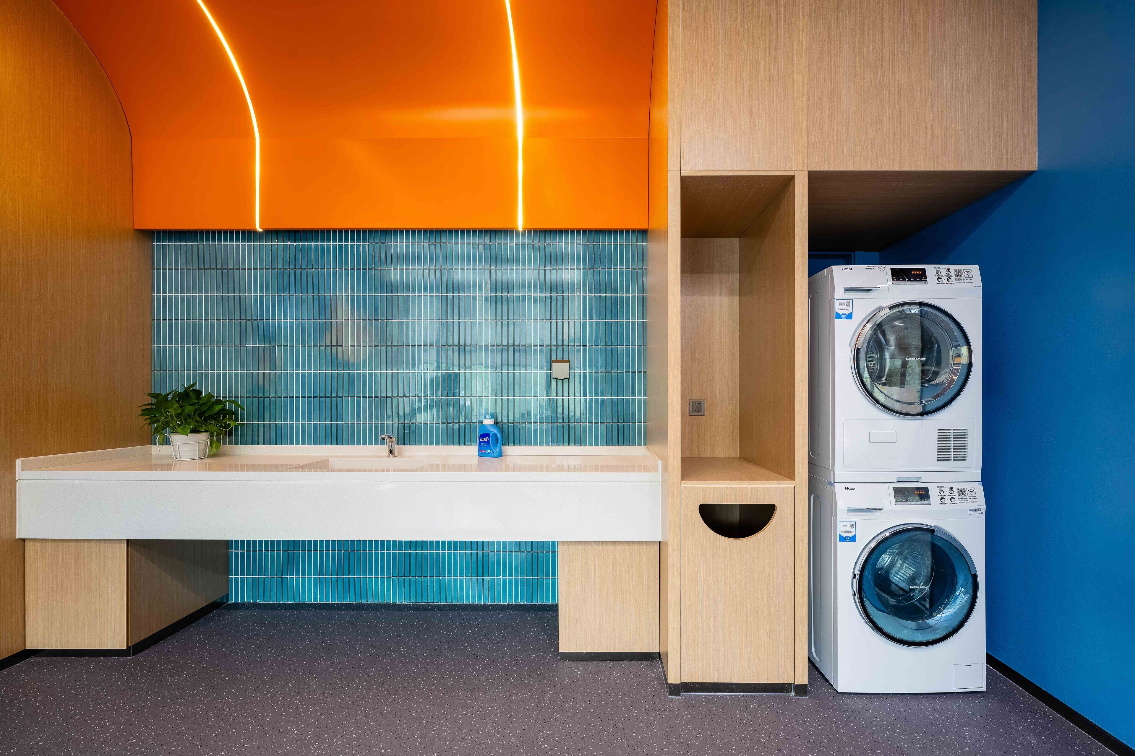 Une salle de bain moderne avec un lavabo, un miroir et des machines à laver superposées.