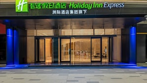 L’entrée d’un hôtel Holiday Inn Express, dotée d’un design moderne, avec de grandes portes vitrées et un intérieur accueillant visible depuis l’entrée.