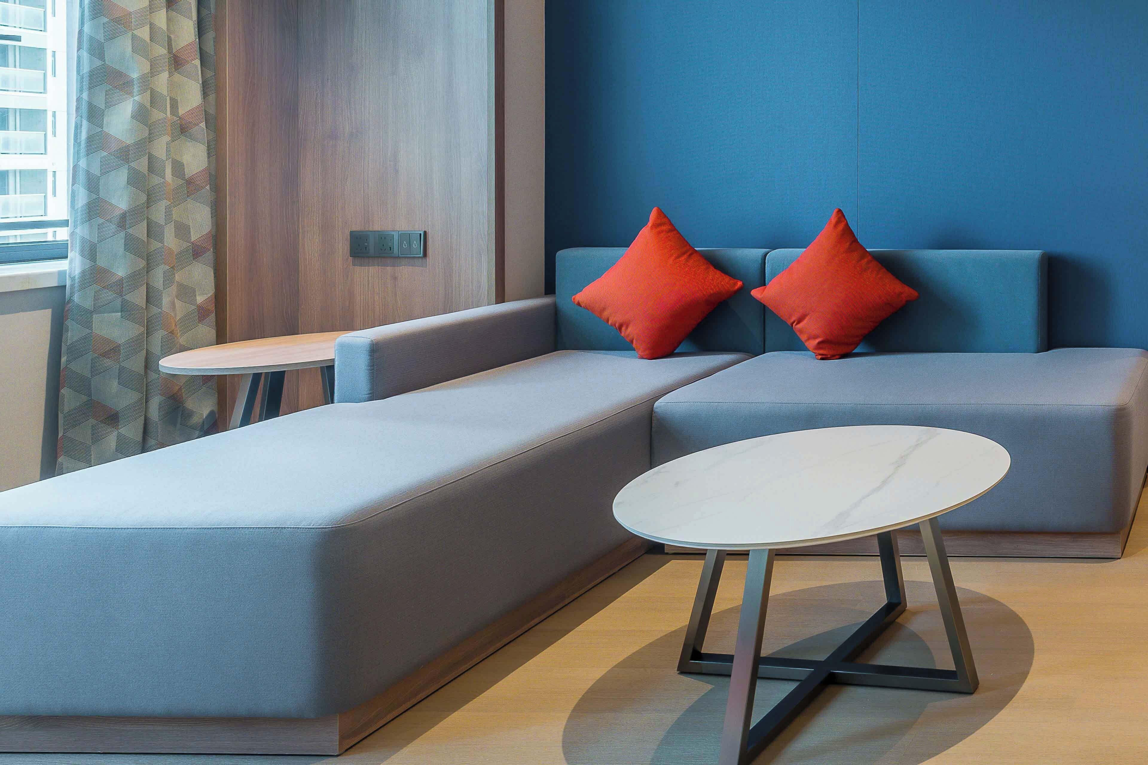 Une pièce moderne avec un canapé et une petite table, une porte en bois et un mur bleu.