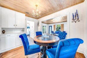 A dining area with a round table and blue upholstered chairs, white cabinetry, and a wooden ceiling. - 2 BD Historic Delray Beach Cottage walk to the Ave (Delray Beach)