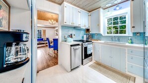A modern kitchen with white cabinets, stainless steel appliances, and a large window providing natural light.