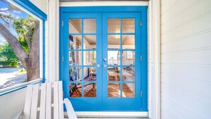 A blue front door with a white porch and a bench.