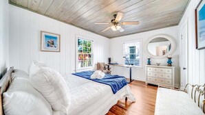 A bedroom with a bed, a dresser, a mirror, and a ceiling fan.