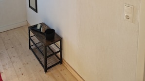 A room with a wooden floor, a black metal bench, two framed pictures on the wall, and a wall-mounted light fixture.