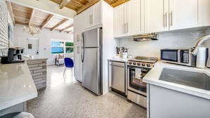 A modern kitchen with white cabinets, stainless steel appliances, and a wooden ceiling. - 2 BD Delray Beach Cottage walk to Atlantic Ave & the beach (Delray Beach)