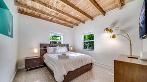 A bedroom with a wooden ceiling, a bed with white bedding, two bedside tables, and a floor lamp. - 2 BD Delray Beach Cottage walk to Atlantic Ave & the beach (Delray Beach)
