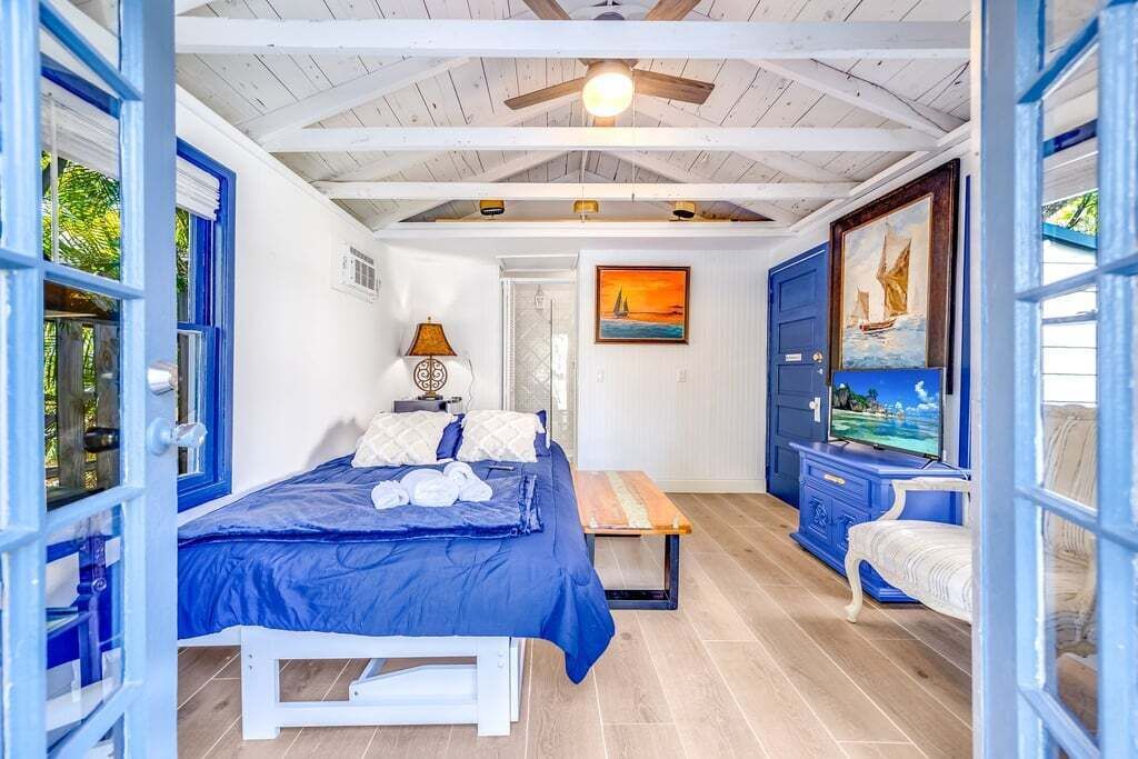 A bedroom with a bed, a bench, a TV, and a painting on the wall.